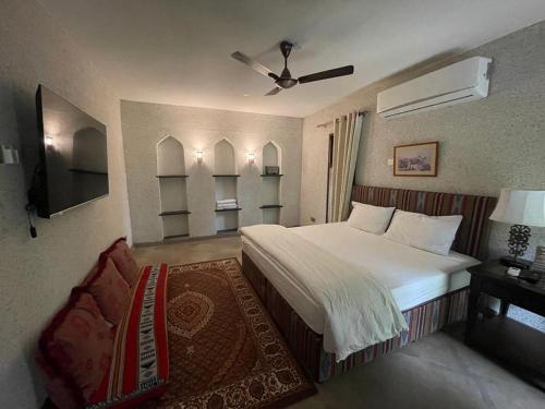 a bedroom with a bed and a chair and a television at Date Palm Inn in Nizwa