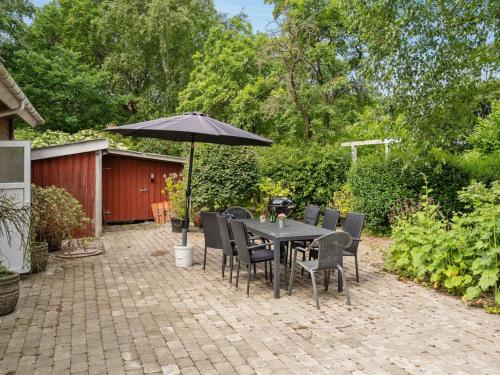 eine Terrasse mit einem Tisch, Stühlen und einem Sonnenschirm in der Unterkunft Holiday Home Jonni - 15km from the sea in Western Jutland by Interhome in Skærbæk