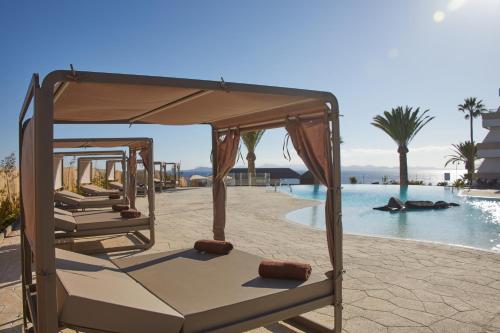 a group of beds sitting next to a swimming pool at Dreams Lanzarote Playa Dorada Resort & Spa in Playa Blanca