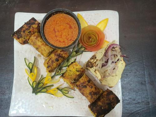 a plate of food with a bowl of dipping sauce at Hotel Mirana , Tinsukia in Tinsukia