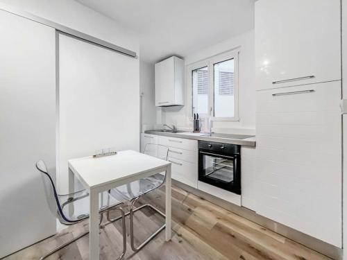 a white kitchen with a small white table in it at Bright studio in the center of Montreux in Montreux