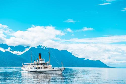 a boat on the water with mountains in the background at Bright studio in the center of Montreux in Montreux