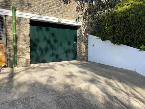 a garage with a green door in a brick building at PALAU - Gran casa de pueblo con fantásticas vistas al mar in Cadaqués