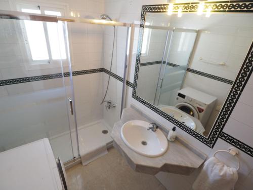 ein Bad mit einem Waschbecken, einer Dusche und einem Spiegel in der Unterkunft Nerja Paradise Rentals - Villa Las Dalias in Nerja