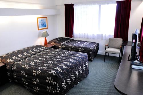 ニュープリマスにあるBraemar Motor Innのベッド2台とデスクが備わるホテルルームです。