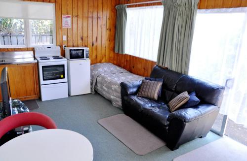 a living room with a couch and a bed and a kitchen at Braemar Motor Inn in New Plymouth