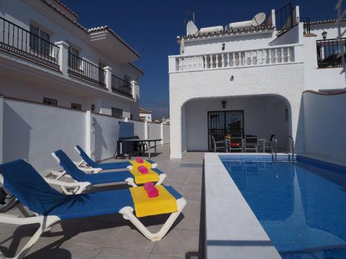 a villa with a swimming pool and some chairs at Nerja Paradise Rentals - Villa Dos Ardillas in Nerja