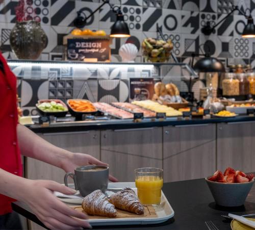 a person holding a tray with pastries on a table at ibis Styles Barcelona City Bogatell in Barcelona