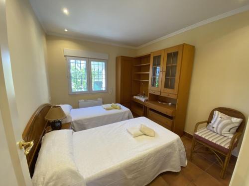 um quarto de hotel com duas camas e uma cadeira em Casa Nieves Cabo roig em Orihuela