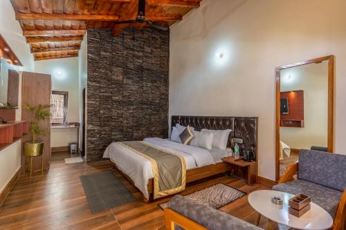 a bedroom with a bed and a couch in a room at SaffronStays Kurmavana, Bhimtal - luxury cottage with pool and lawn - All clear roads in Bhīm Tāl