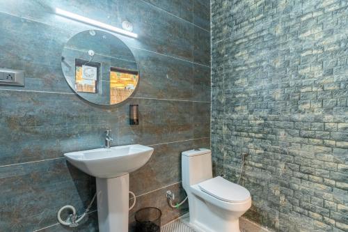 a bathroom with a sink and a toilet and a mirror at SaffronStays Kurmavana, Bhimtal - luxury cottage with pool and lawn - All clear roads in Bhīm Tāl