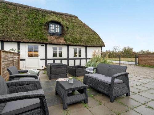 un patio con muebles y una casa con techo de hierba. en Apartment Thessa - 900m from the sea in SE Jutland by Interhome, en Juelsminde
