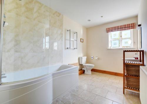 a bathroom with a tub and a toilet at Oak Lodge in Alderford