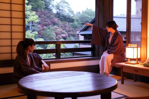 two women sitting on a balcony looking out of a window at Fujiya in Minamioguni