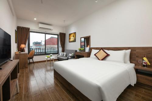 a bedroom with a large white bed and a television at Hanoi Saga Hotel in Hanoi