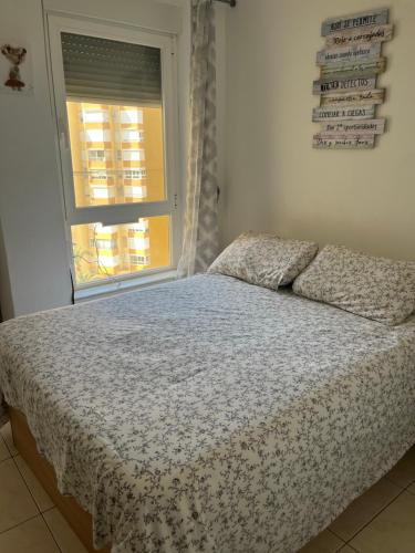 1 cama en un dormitorio con ventana y colcha en Estudio fran centro internacional, en Algarrobo Costa