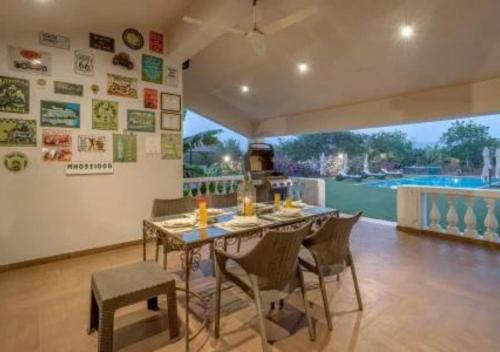a dining room with a table and chairs and a pool at SaffronStays Brunton House, Alibaug - luxury pool villa near Awas Beach in Alibaug