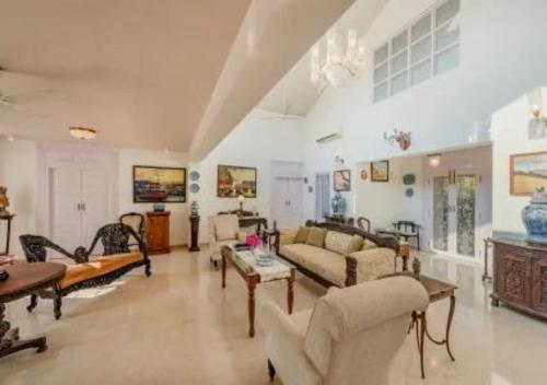 a large living room with couches and tables at SaffronStays Brunton House, Alibaug - luxury pool villa near Awas Beach in Alibaug