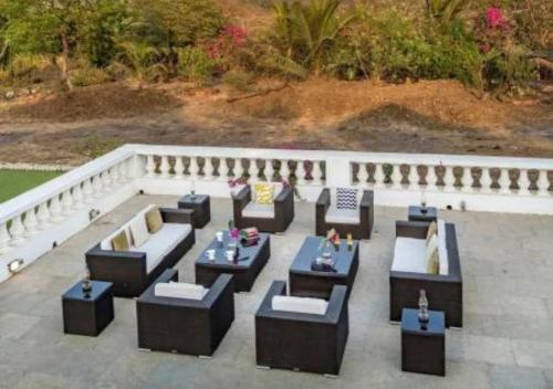 a group of couches and tables on a patio at SaffronStays Brunton House, Alibaug - luxury pool villa near Awas Beach in Alibaug