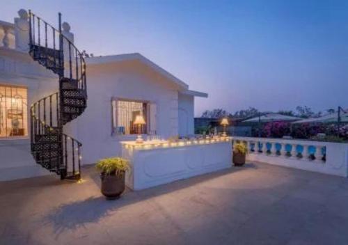 a white house with a staircase and a patio at SaffronStays Brunton House, Alibaug - luxury pool villa near Awas Beach in Alibaug
