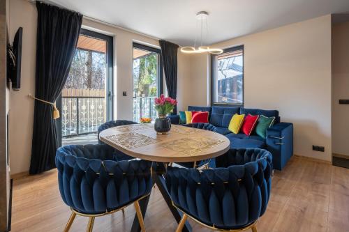 a living room with a blue couch and a table and chairs at Rezydencja Strążyska & Chalet BBQ in Zakopane