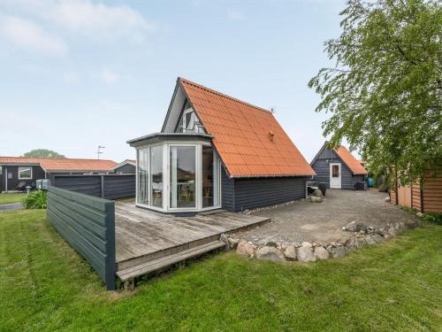 uma casa com um telhado laranja e um deque de madeira em Holiday Home Leve - 200m from the sea in SE Jutland by Interhome em Sønderby