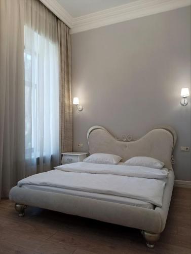 a bedroom with a white bed with a window at Hotel Menshikov in Odesa