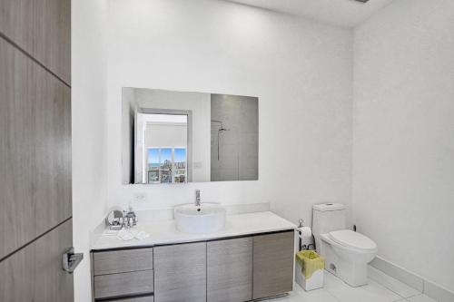 a white bathroom with a sink and a toilet at Modern Penthouse condo with 2 story private terrace in Hollywood