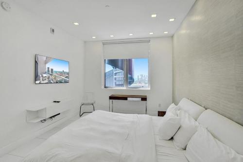a white bedroom with a large white bed and a desk at Modern Penthouse condo with 2 story private terrace in Hollywood
