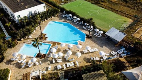 トレ・フォンターネにあるZahira Resortのプールと椅子、テニスコートの空中の景色を望めます。