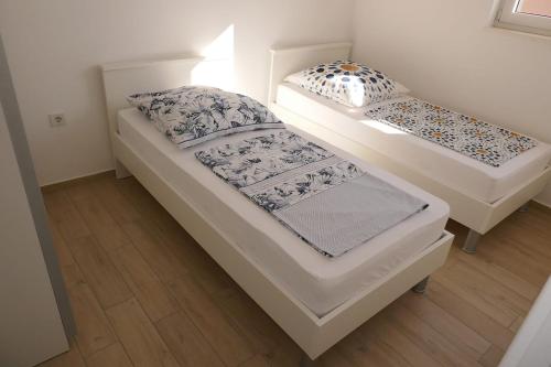 Duas camas num pequeno quarto com pisos em madeira em Apartmani Villa Ana, Sibenik - Brodarica em Brodarica
