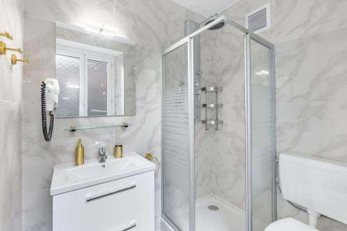 ein weißes Bad mit einer Dusche und einem Waschbecken in der Unterkunft Exquisite one-bedroom apartment on Av du Casino in Montreux