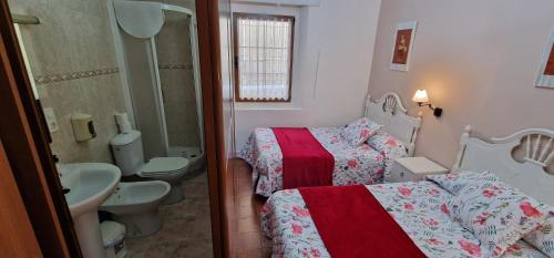 a bathroom with two beds and a sink and a toilet at Río España - Casa amplia con patio y barbacoa en Villaviciosa in Villaviciosa
