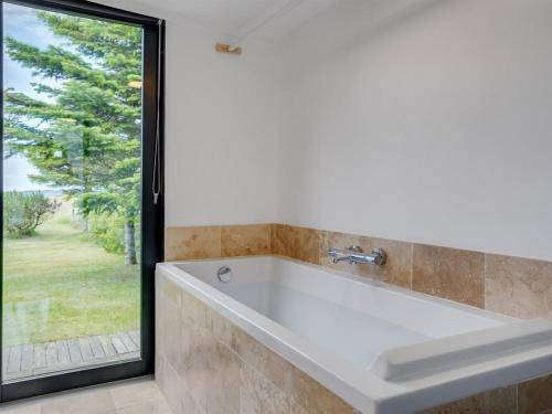 La salle de bains est pourvue d'une baignoire blanche et d'une fenêtre. dans l'établissement Holiday Home Lok - all inclusive - 90m to the inlet by Interhome, à Roslev