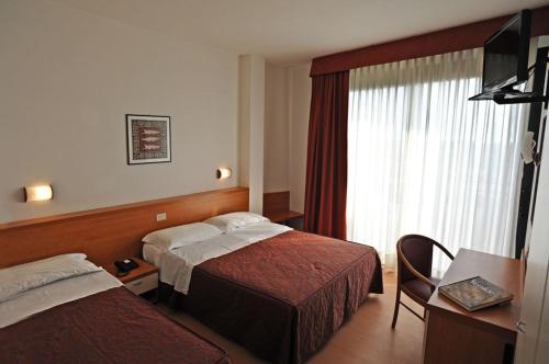 a hotel room with two beds and a window at Hotel Fenix in Cavallino-Treporti