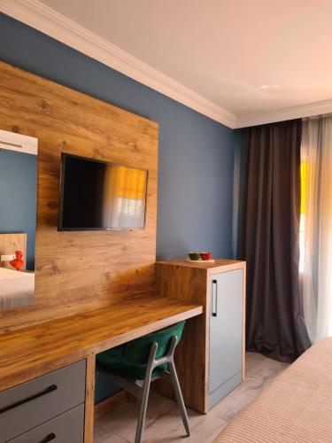 a bedroom with a desk with a television on a wall at Ekin Otel Göcek in Göcek