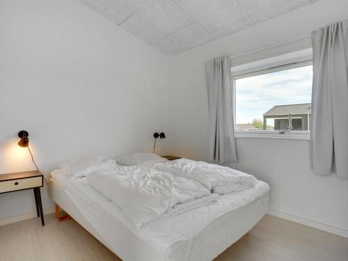 a white bedroom with a bed and a window at Holiday Home Nimrod - 300m from the sea by Interhome in Odder