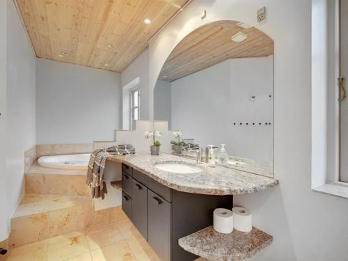 ein Badezimmer mit einem Waschbecken, einem Spiegel und einer Badewanne in der Unterkunft Holiday Home Malinda - 500m from the sea in SE Jutland by Interhome in Odder