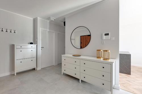 um quarto branco com uma cómoda e um espelho em Seaside Amber Apartment with AC by Blue Mandarin em Gdansk