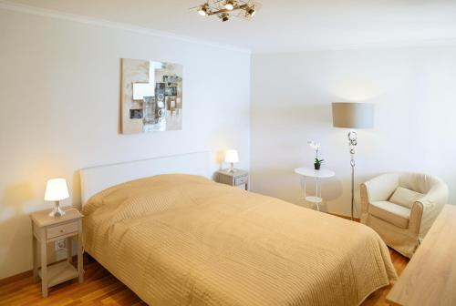 a white bedroom with a bed and a chair at Lake View - Appt Central 2 Bedroom, 1 Bath in Montreux