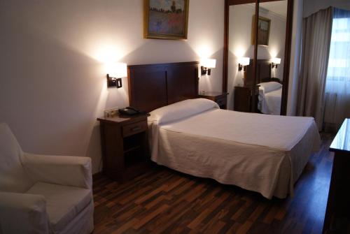 a hotel room with a bed and a chair at Hotel Mulhacen in Guadix