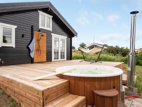einen Whirlpool auf einer Terrasse mit einem schwarzen Haus in der Unterkunft Holiday Home Siebelt - 200m from the sea in Djursland and Mols by Interhome in Knebel