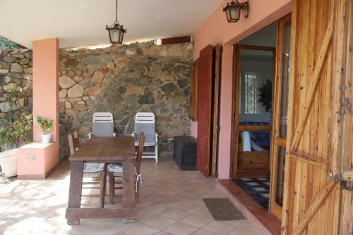 patio ze stołem i kamienną ścianą w obiekcie Villa Olivastro w mieście Torre delle Stelle