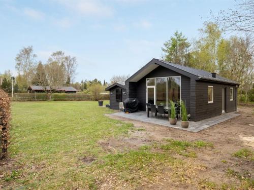 una pequeña casa negra con un gran patio en Holiday Home Sunja - 450m from the sea in Djursland and Mols by Interhome, en Brøndstrup
