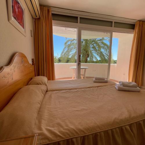 a bedroom with a bed and a large window at Apartamentos Coronado in Marbella