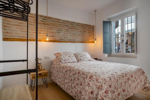 a bedroom with a bed and a brick wall at Apartamento Essence by Solset in Frigiliana