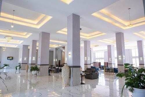 un gran vestíbulo con columnas y sillas en un edificio en The Voice Hotel, en Entebbe