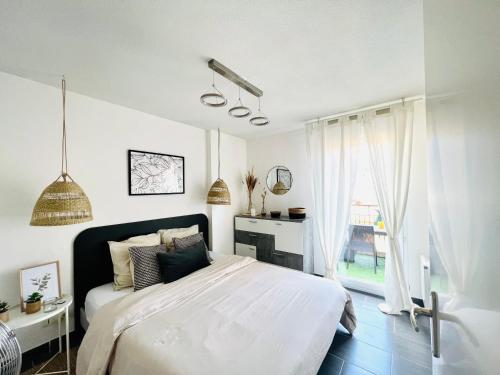 a white bedroom with a bed and a window at Les Jardins des Senteurs - Appartement privé avec piscine et parking in Grasse