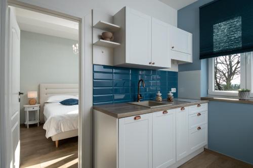 uma cozinha com armários brancos e paredes azuis e uma cama em Apartments Pausa em Žminj