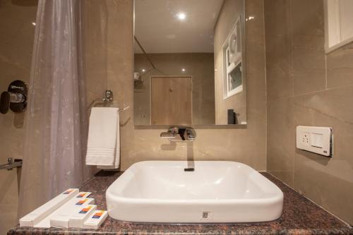 a bathroom with a white sink and a mirror at MySpace Kadison in Dāvangere